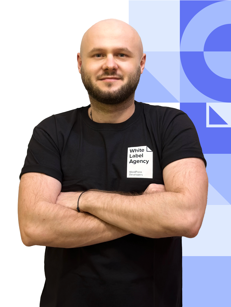 A bald man with a beard and mustache, wearing a black t-shirt featuring the "White Label Agency" logo. He is posing with his arms crossed.