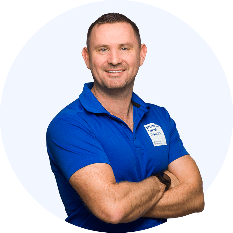 A man in a blue shirt representing White Label Agency, smiling and having his arm crossed