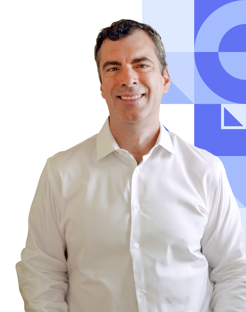 A smiling man with short, dark hair, wearing a white button-down shirt.